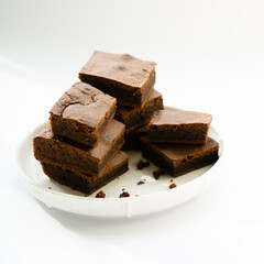 Chocolate brownie sliced into square slices on a white plate.
