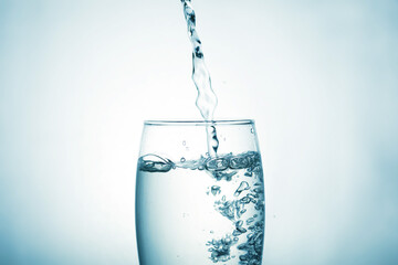 Close up of pouring purified drinking water from a bottle with bubbles and splashes on a white background