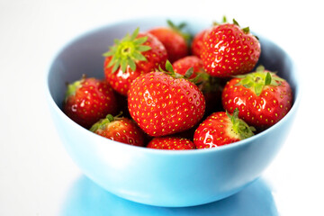 ripe strawberries in a blue bowl on a white background close up
