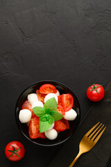 Healthy eating concept. Tasty summer salad with mozzarella and cherry tomatoes. Top view with copy space. Dark slate background.