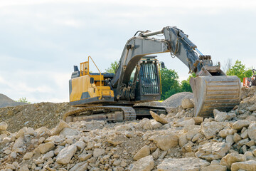 Obraz premium A yellow excavator on a pile of gravel