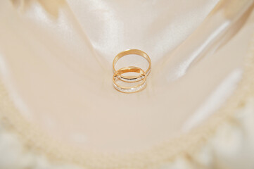 Reflejo dentro de un anillo de diamantes de oro junto a otro anillo con un fondo de tela satinada.