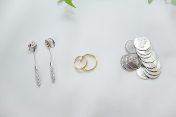 Arras monedas para bodas. Monedas de plata junto con otros accesorios de boda como anillos de oro y pendientes.