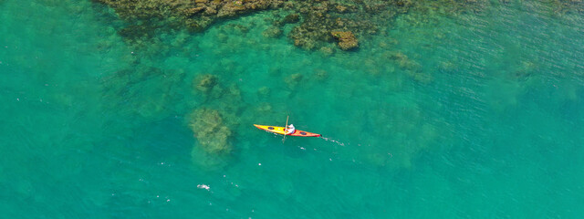 Aerial drone ultra wide panoramic photo with copy space of woman paddling on tropical island exotic turquoise calm sea