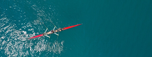Aerial drone ultra wide photo of young women athletes rowing in canoe competition in tropical lake...
