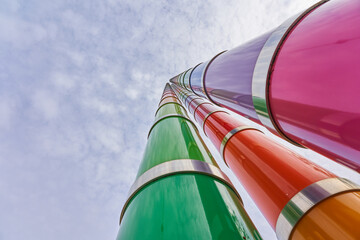 3 colorful masts protrude into the blue cloudy sky, deep perspective, ultra wide angle. Stuttgart, Germany.