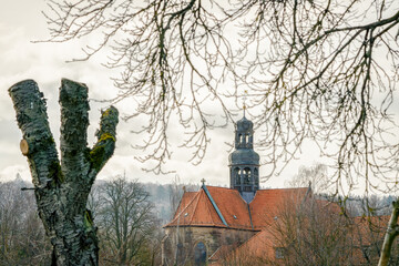 An old monastery in the background with trees and branches in the foreground