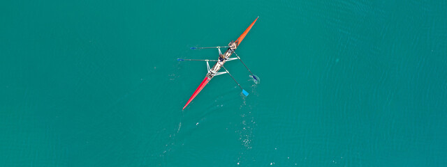 Aerial drone ultra wide photo of young women athletes rowing in canoe competition in tropical lake...