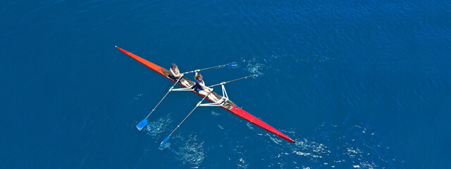 Aerial drone top ultra wide panoramic view of sport canoe rowing synchronous female athletes...