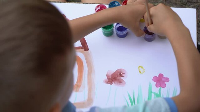 Closeup top view video footage of little kid of 5 years old painting cute childish picture together with his mommy.