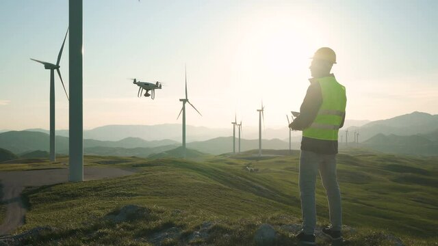 Technician Engineer in Wind Turbine Power Generator Station launches a drone for visual control of generators