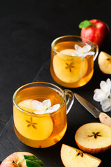 Homemade fermented kombucha or cider in glasses with a slice of apple on a dark stone table. A healthy probiotic kombucha refreshing drink. Copy space.