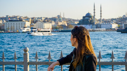 Woman watching Bosphorus in Karakoy or Eminonu, European side of Istanbul City under blue sky.