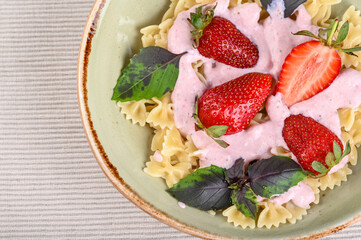 Obraz na płótnie Canvas Pasta with strawberry cream and fresh strawberries and basil
