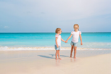 Adorable little girls have a lot of fun on the beach.