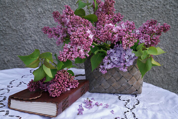 Lilac flowers in basket with book on table