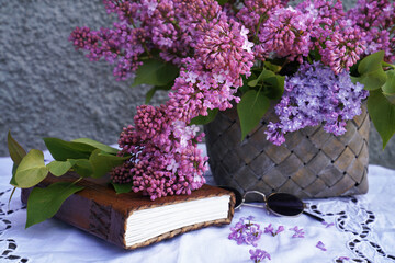 Lilac flowers in basket with book on table