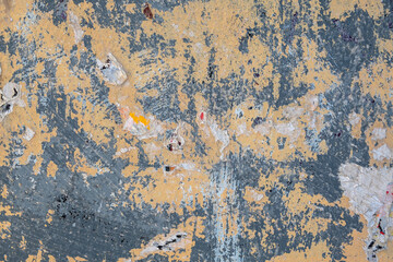 old gray beige wall with spots and stripes, paint scratches with scraps of paper ads. rough surface texture