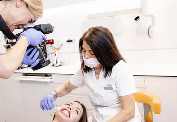 Dentist photographing a young patient's mouth while the nurse holds her mouth open.