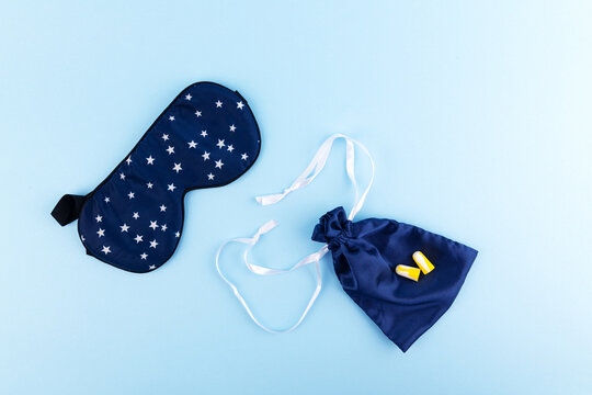 Good sleep concept: blue sleep mask and earplugs on blue background. Accessories for good rest at night, block of any light and sound.