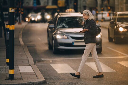 Senior woman walking on zebra crossing in city