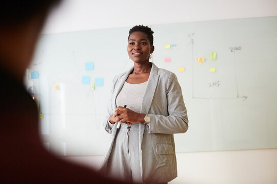 Smiling female entrepreneur looking away during presentation in office seminar