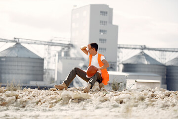 Engineer near the factory. Man in a helmet. Inspector looks at the building.