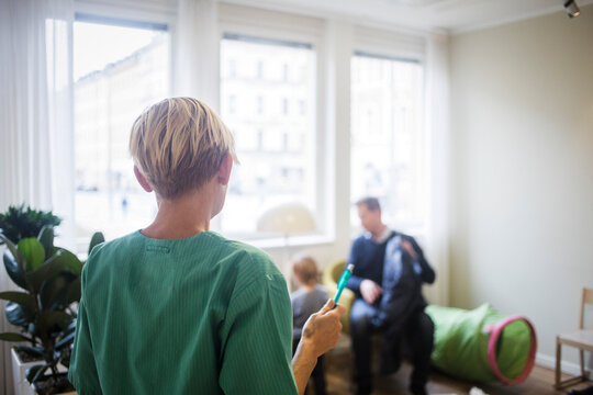 Rear view of pediatrician with pen standing in hospital