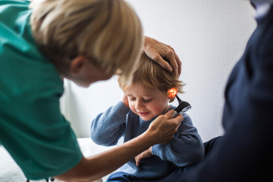 Female doctor examining boy's ear with otoscope in hospital
