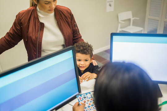 High angle view of boy standing by mother looking at pediatrician with stickers in hospital
