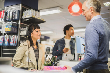 Smiling female customer talking to mature owner in electronics store