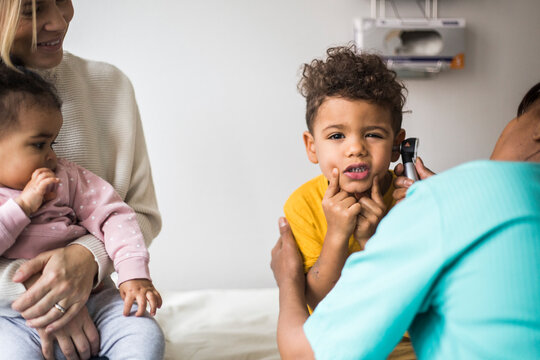 Portrait of boy making faces during ear examination by female doctor in clinic