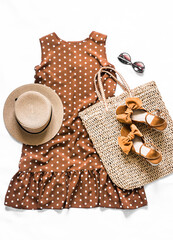 Women's clothing - brown polka dot dress, straw tote bag, suede wedge sandals, sunglasses on a...