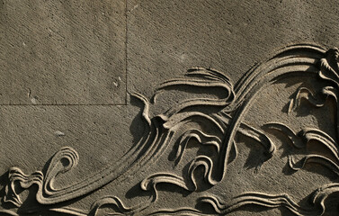 A beautiful floral arabesque relief decoration. Detail of an old luxury villa natural stone cladding.