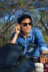 Fototapeta na wymiar Young male model showing lifestyle and listening music on motor cycle or bike
