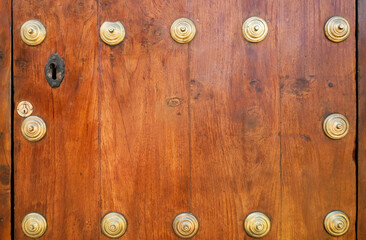 A key hole and golden metal buttons on a classic varnished wood doors.