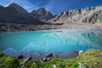 Turquoise lake Gradensee at Nossberger Hut, mountains and reflection on water surface, in Gradental in national park Hohe Tauern, Austria.