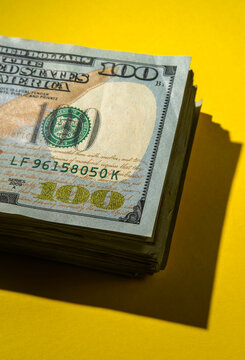 Stack of 100 dollar bills on yellow background