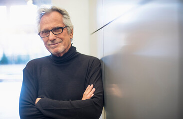 Portrait of smiling senior man standing in office corridor