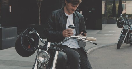 Biker drinking coffee while standing near motorcycle