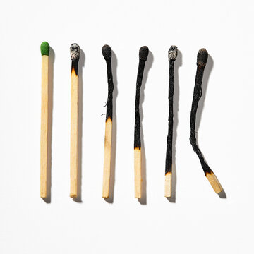 Row of burnt matchsticks on white background