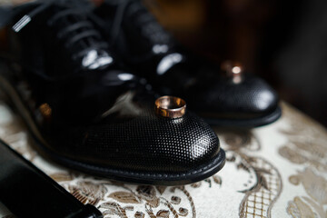 Fototapeta na wymiar The groom is gathering in the morning. Gray chair. Men's Black classic patent leather shoes. Black belt. Wedding details. Eau de toilette, perfume, leather strap watch. Wedding rings.
