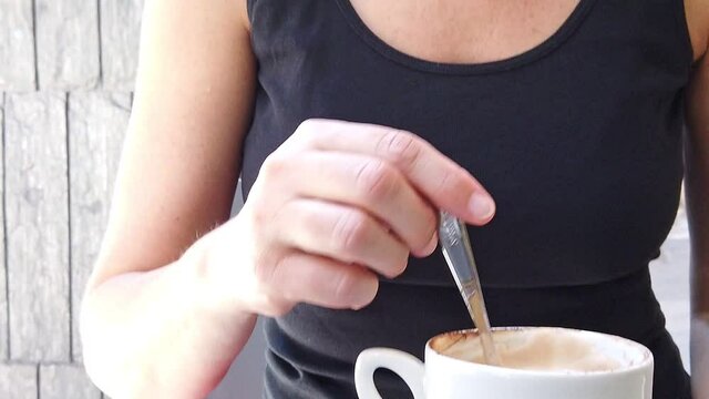 SLOW MOTION: girl with a surgical mask drinking a cappuccino coffee cup in a typical Italian cafe of Bologna city. Coronavirus after COVID-19 lockdown with social distancing in Italy.