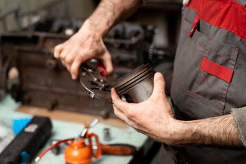 Car worker repair a pistons in autoservice. Piston defective checking.