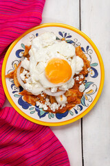 Mexican red chilaquiles with fried egg on white background