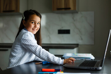 Little girl studying online using her laptop at home