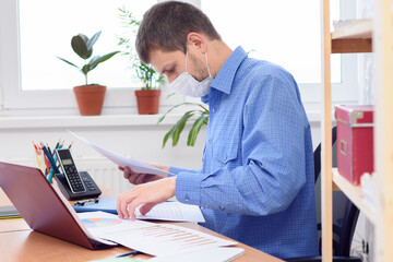 office worker in medical mask disassembles documents on the desktop