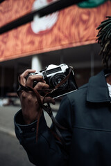 beautiful afro black man outdoor in the city holding instant camera, shooting - photography, creative, artist concept