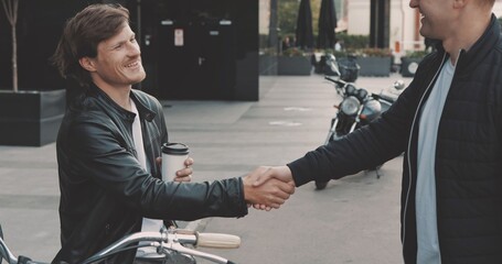 Two friends motorcyclists men meet on street