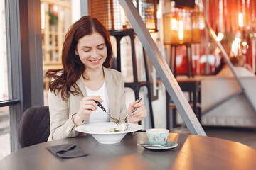 Girl in a cafe. Woman in a brown jacket. Lady with pasta and tea.